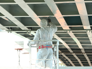 Professional worker in a protective suit and mask paints a bridg Polyurea Coatings Application